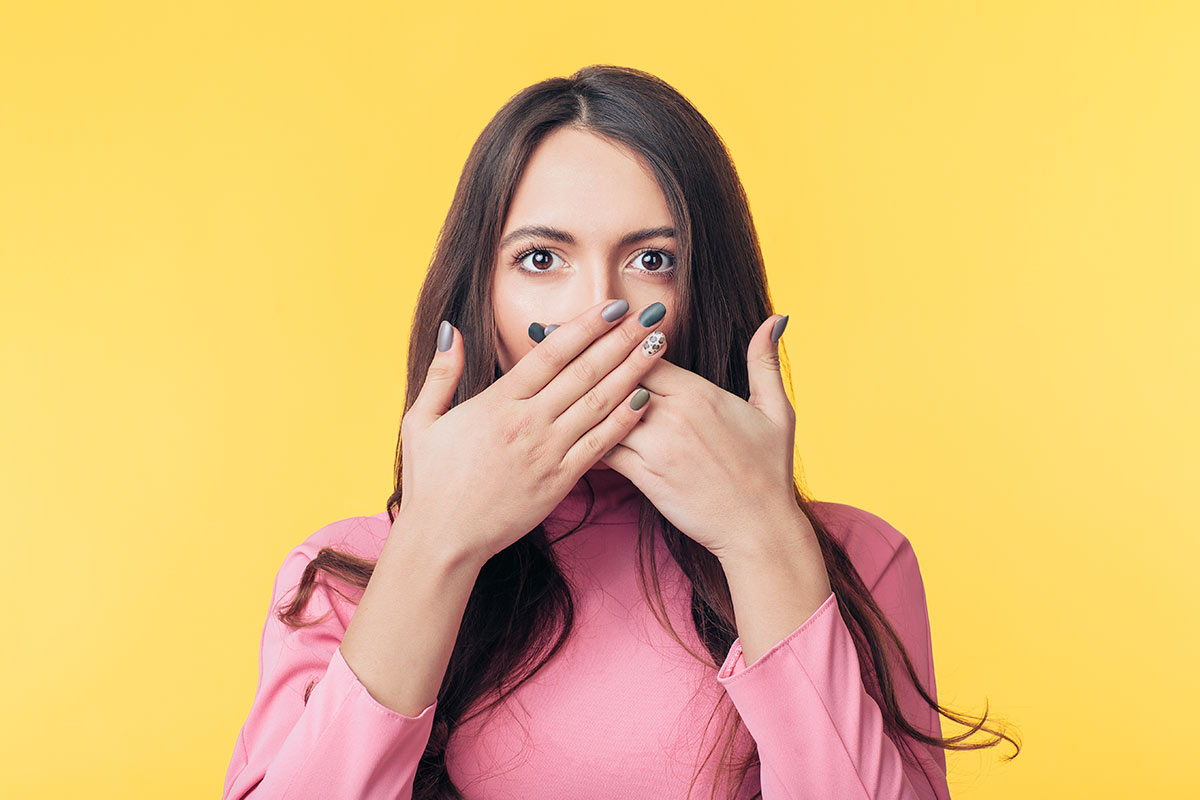 Chica cubriéndose la boca por mal alieto