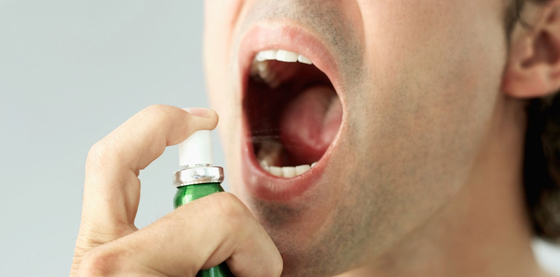 Hombre abriendo la boca para echarse spray bucal
